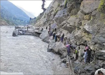  ?? Sherin Zada Associated Press ?? RESIDENTS CROSS a destroyed road Sunday in Pakistan’s Kalam Valley. More than 1,300 people have been killed and millions displaced by unusually heavy monsoon rains that many experts blame on climate change.