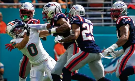  ?? BARRY CHIN/GLOBE STAFF ?? Kyle Dugger leveled the Dolphins’ Braxton Berrios with a stiff arm during a 15-yard, first-quarter intercepti­on return.