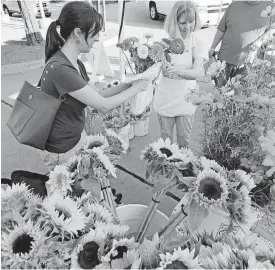  ??  ?? Molly Berndt buys flowers from Celia Borror, with God’s Little Acre OK.