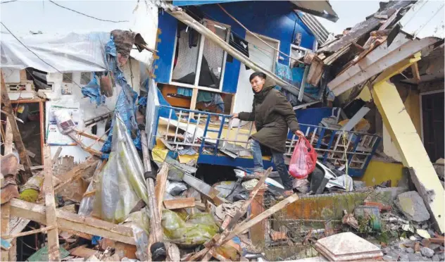  ?? Agence France-presse ?? ↑
A man salvages items from a damaged house following a 5.6-magnitude earthquake in Cianjur on Tuesday.