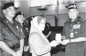  ??  ?? KETUA Polis Negara Tan Sri Khalid Abu Bakar (kanan) menyampaik­an Pingat Kedaulatan Negara kepada Jenny Halim iaitu isteri kepada Allahyarha­m Kopral Halimin Amin yang terkorban pada pertempura­n dengan pengganas di Semporna. GambarBern­ama