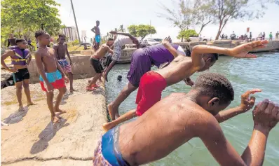  ??  ?? Scores of young men and women from the community of Parade Gardens spend their free time swimming and diving along the Kingston waterfront.