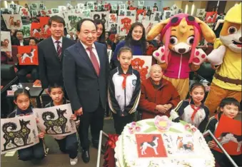  ?? JIANG DONG / CHINA DAILY ?? Zhou Lingzhao (middle in red), 99, attends a ceremony in Beijing to issue the Year of the Dog stamps he designs. A cake to mark the release bears the stamps’ patterns.