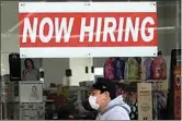  ?? JEFF CHIU / AP ?? In this May 7 file photo, a man wearing a mask walks under a Now Hiring sign at a CVS Pharmacy during the coronaviru­s outbreak in San Francisco.