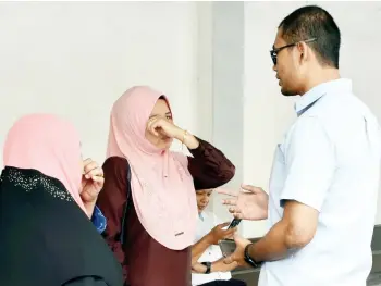  ??  ?? Rafeah in tears (left) being consoled by a friend outside the court yesterday.
