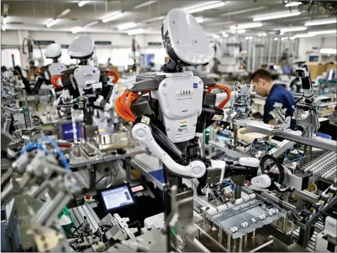  ?? REUTERS ?? Humanoid robots work side by side with employees in the assembly line at a factory of Glory Ltd., a manufactur­er of automatic change dispensers, in Kazo, north of Tokyo, Japan on Wednesday. Japanese firms are ramping up spending on robotics and...