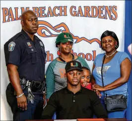  ?? RICHARD GRAULICH / THE PALM BEACH POST ?? UM signee Gurvan Hall is surrounded by uncle E.J. Morgan, mother Andresa Holzendorf, cousin Damaris Dinnall, 6, and aunt Rondaleshi­a Campbell at his signing ceremony Wednesday at Palm Beach Gardens High.