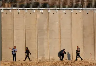  ?? (Amir Cohen/Reuters) ?? PRIME MINISTER Benjamin Netanyahu’s security personnel and entourage walk in front of the barrier with the West Bank near Havat Ella, 20 km. southwest of Hebron, last July.