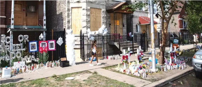  ?? ASHLEE REZIN/SUN-TIMES ?? Crosses, balloons and photos were part of a memorial for nine children who were killed in a fire that broke out Sunday in a building behind this three-story greystone apartment building in Little Village.