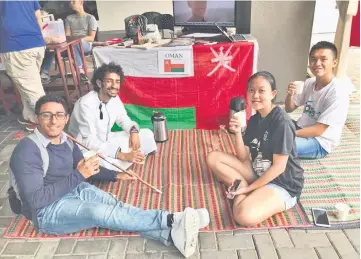  ??  ?? Students from Oman welcome visitors to their ‘home’ where they sit on a mat while enjoying some Omani tea.