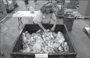  ?? The Associated Press ?? BACKPACK BUDDIES: Cindy Gustafson helps pack bags of food for the Backpack Buddies program Friday at Second Harvest Food Bank in Nazareth, Pa. The program faces a loss of federal funding under the budget proposed by President Donald Trump’s...