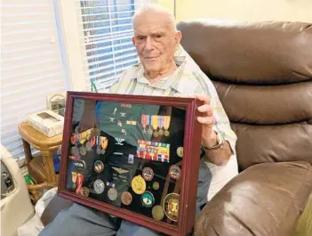  ?? STEPHEN HUDAK/ORLANDO SENTINEL ?? Retired U.S. Navy Capt. Richard “Robbie” Roberts holds a shadow box containing the medals and honors he earned during his decorated military service. A naval aviator in World War II, Roberts will mark his 107th birthday Saturday. He is among a small handful of World War II centenaria­n veterans.