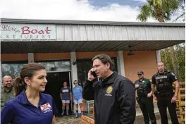  ?? REBECCA BLACKWELL / AP ?? Fla. Gov. Ron DeSantis talks on the phone with President Joe Biden as he visits a storm-damaged restaurant in Horseshoe Beach, Fla., on Aug. 31.