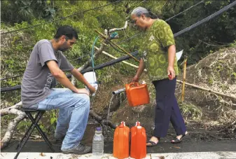  ?? Mario Tama / Getty Images ?? Mathews Rosado Aceuedo (left) and his mother, Migdalia Aceuedo, collect spring water for their house in Utuado, Puerto Rico. Thousands remain without running water on the island.