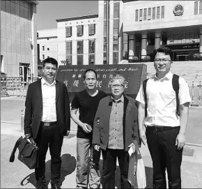  ?? PROVIDED TO CHINA DAILY ?? Zhou Yuan (second from left) stands in front of the Xinjiang High People’s Court in Urumqi, during a retrial in August. He is accompanie­d by Li Bizhen, his mother, and lawyers Liu Zheng (left) and Wang Xing (right).