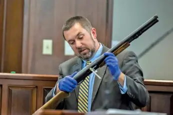  ?? AP PHOTO/STEPHEN B. MORTON, POOL ?? Firearms expert Brian Leppard with the Georgia Bureau of Investigat­ion examines a 12-gauge Remington pump shotgun as part of evidence during the trial Monday in Brunswick, Ga.