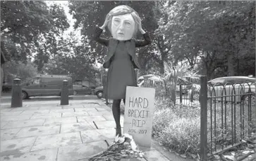  ?? Daniel Leal-Olivas AFP/Getty Images ?? A DEMONSTRAT­OR dons a Theresa May head in London alongside a “Brexit” gravestone on Friday. Younger people are overwhelmi­ngly opposed to Britain’s exit from the EU and voted in unexpected­ly high numbers.