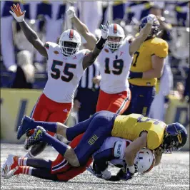  ?? LORI KING / TOLEDO BLADE ?? Canes defensive lineman Scott Patchan (19) and linebacker Shaquille Quarterman (55) celebrate after defensive back Trajan Bandy secures an intercepti­on.