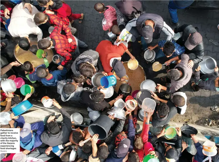  ?? Reuters ?? Palestinia­ns gather to receive food from a charity kitchen, with the majority of the Gazans experienci­ng food shortages