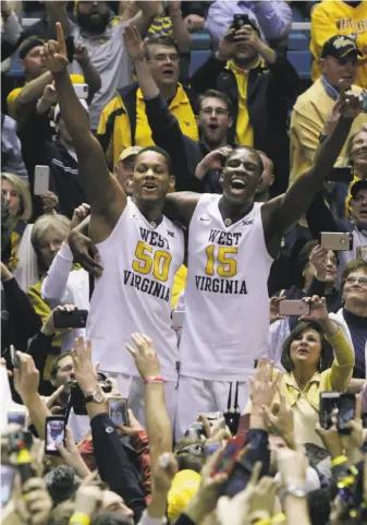  ?? Ray Thompson / Associated Press ?? West Virginia’s Sagaba Konate (50) and Lamont West join the crowd in celebratin­g the Mountainee­rs’ victory over top-ranked Baylor, inspiring a flurry of smartphone photos.