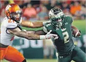  ?? Joseph Garnett Jr. Getty Images ?? RUNNING BACK D’Ernest Johnson of No. 22 South Florida repels Illinois defensive back Patrick Nelson.