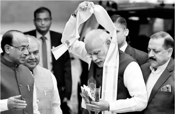  ??  ?? Modi removes a stole given to him by a minister upon his arrival at the Parliament on the first day of the winter session in New Delhi. — Reuters photo