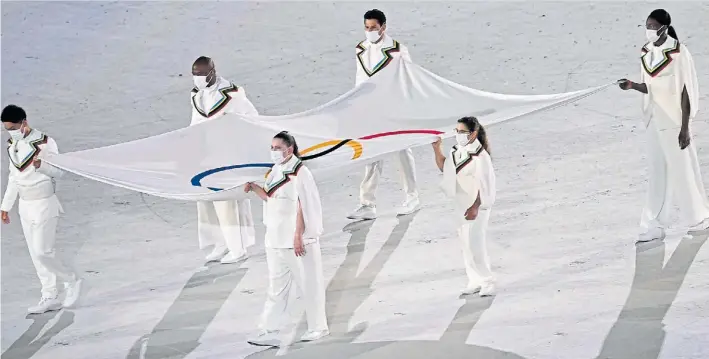  ?? AFP ?? La Peque, gigante. Paula Pareto sostiene la bandera olímpica con cinco atletas más que, como ella, fueron elegidos por sus valores y haber ayudado en la lucha contra el coronaviru­s.