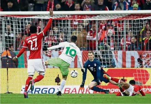  ??  ?? Top form: Bayern Munich’s Manuel Neuer (second from right) saving a shot by Wolfsburg’s Yunus Malli during their German Cup match at the Allianz Arena on Tuesday. Bayern won 1- 0. — AP