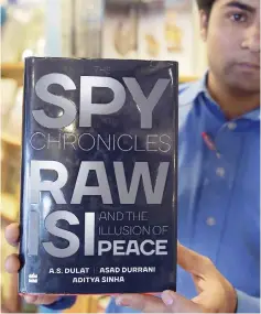  ??  ?? A Pakistani bookstore employee displays a copy of the book ‘The Spy Chronicles: RAW, ISI and the Illusion of Peace’. — AFP photo