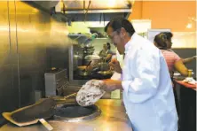  ??  ?? Chef Prem Tamang, left, makes naan at his S.F. restaurant Cuisine of Nepal. Above: The superlativ­e chicken cashew curry.