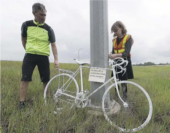  ?? GREG SOUTHAM ?? Jonathan Woelber and Coreen Shewfelt from the Edmonton Bicycle Commuters Society install a ghost bike on Highway 14 near Highway 216 Friday. A cyclist was killed after being struck by an eastbound 2004 Pontiac Sunfire in the area southeast of Edmonton...