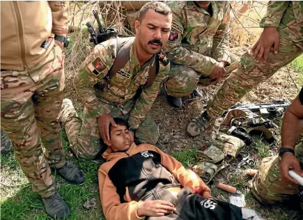  ?? REUTERS ?? Iraqi Rapid Response Force soldiers treat a boy wounded during fighting with Islamic State militants in southwest Mosul yesterday.