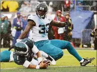  ?? Tim Nwachukwu / Getty Images ?? Eagles quarterbac­k Jalen Hurts dives past the Jaguars’ Devin Lloyd while scoring a touchdown during the second quarter on Oct. 2 in Philadelph­ia.