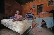  ?? AP PHOTO/ERALDO PERES ?? On March 22, Bruno Ferreira and his son Davi sit on the only bed in their one-room home they built in the Sol Nascente favela of Brasilia, Brazil.