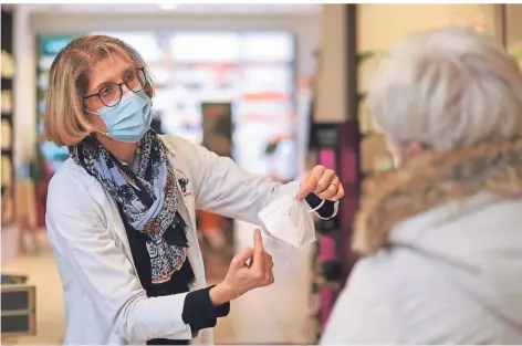  ??  ?? Viel zu tun: Apothekeri­n Catharina Buff von der Einhorn-Apotheke in Kleve erklärt einer Kundin die Handhabung der FFP-2-Maske.