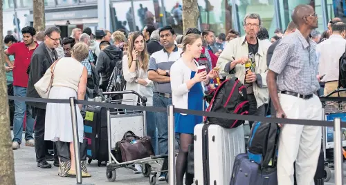  ??  ?? Passengers queue up outside Heathrow Airport yesterday after a major IT problem caused British Airways to cancel most flights