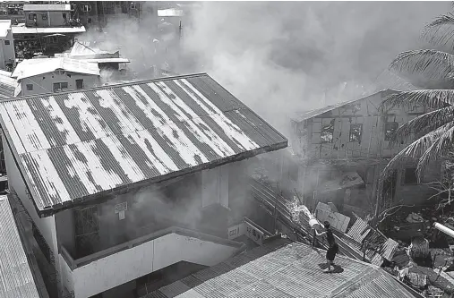  ??  ?? A RESIDENT splashes water on the two-floor classroom of Zonta Elementary School as fire hits Isla Verde in Barangay 23-C, Poblacion District on Friday afternoon. BING GONZALES