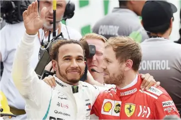  ??  ?? Lewis Hamilton (left) waves at the crowd as he hugs Sebastian Vettel after winning his fifth drivers’ title after the F1 Mexico Grand Prix at the Hermanos Rodriguez circuit in Mexico City. — AFP photo