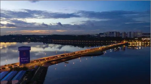  ?? (Bloomberg (WPNS)/SeongJoon Cho) ?? Commercial and residentia­l buildings stand in Singapore (right) as vehicles travel along the Causeway across the Straits of Johor at dawn above Johor Bahru, Malaysia, in 2019.