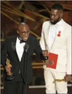  ??  ?? Barry Jenkins, left, and Tarell Alvin McCraney accept the award for best adapted screenplay for “Moonlight” at the Oscars on Sunday at the Dolby Theatre in Los Angeles.