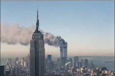  ?? AP PHOTO/MARTY LEDERHANDL­ER, FILE ?? In this Sept. 11, 2001, file photo, the twin towers of the World Trade Center burn behind the Empire State Building in New York.