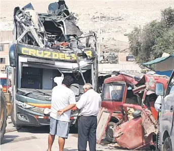  ?? — AFP photo ?? Men look at a a double-decker bus that crashed into parked cards on the Pan American Highway in the Arequipa region, southern Peru.