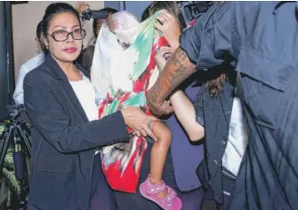  ?? | FIRDIA LISNAWATI/ AP ( ABOVE); AP ( RIGHT) ?? ABOVE: Security guards and a lawyer escort 2- year- old Stella Schaefer ( center, coveredwit­h a scarf) as the child leaves Kerobokan Prison with Australian Balinese woman Oshar Putu Melody Suartama, also partially covered by the scarf. RIGHT: Heather...