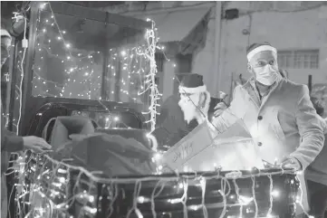  ?? MAYAALLERU­ZZO/AP ?? Volunteers froma Catholic men’s group distribute presents to children on Christmas Eve fromthe back of amotorized rickshaw in the Christian Quarter of the Old City of Jerusalem.