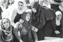  ?? Ozan Kose / AFP / Getty Images ?? Relatives mourn Saturday at the grave of Halil Yagmur, who was killed in a mortar attack a day earlier in Suruc, Turkey.