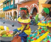  ?? DAVID FREID THE NEW YORK TIMES ?? Palenquera­s, Afro-caribbean women from nearby San Basilio de Palenque, the first free African settlement in the Americas, sell fruit common to the region.