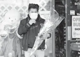  ?? NAM Y. HUH/AP ?? A man carries his purchase out of a flower shop Saturday in Morton Grove, Illinois. Many families that were separated by lockdowns imposed because of the pandemic last year made plans for long-awaited reunions Sunday for Mother’s Day.