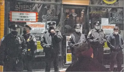  ?? Irene Spezzamont­e The Associated Press ?? Officers stand Tuesday outside Mac’s Public House in Staten Island, where a co-owner was accused of defying virus restrictio­ns.