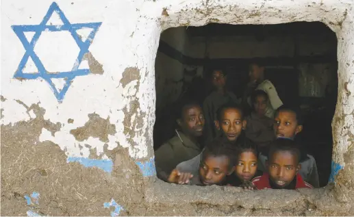  ?? (Eliana Aponte/Reuters) ?? ETHIOPIAN CHILDREN, whose roots trace back to Judaism, look out of a window at a Beta Israel school while awaiting immigratio­n to Israel, in Gondar in 2007.