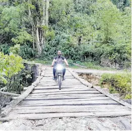  ?? ?? A man drives his motorcycle on the wooden structure fixed by residents at the Woodsville Bridge in Woodsville, Hanover.